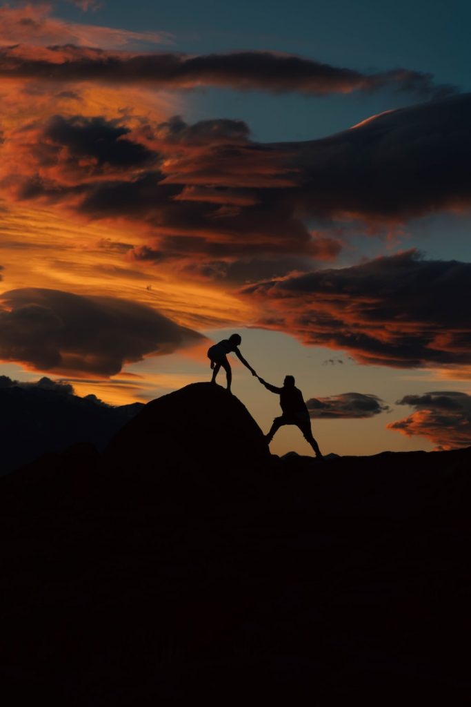 a couple of people holding hands on top of a hill