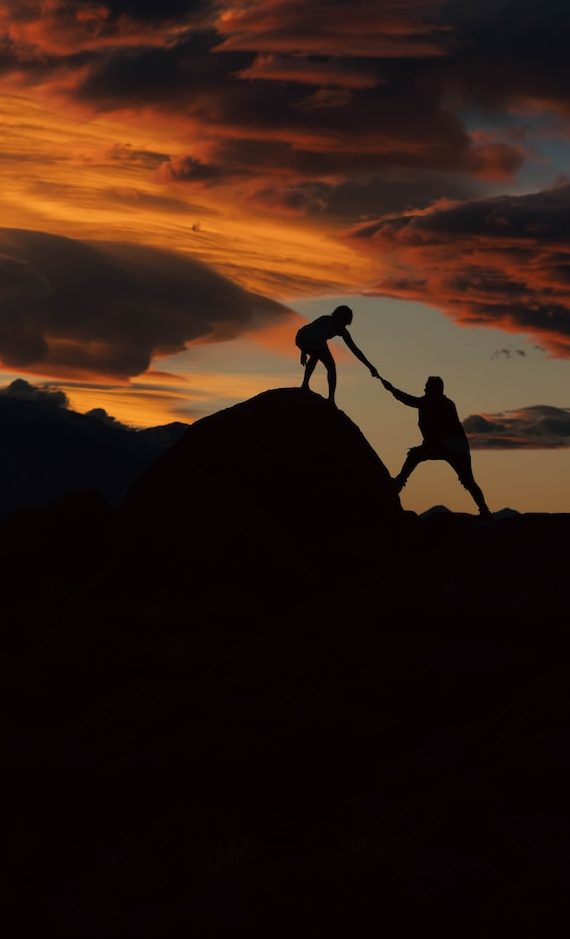 a couple of people holding hands on top of a hill